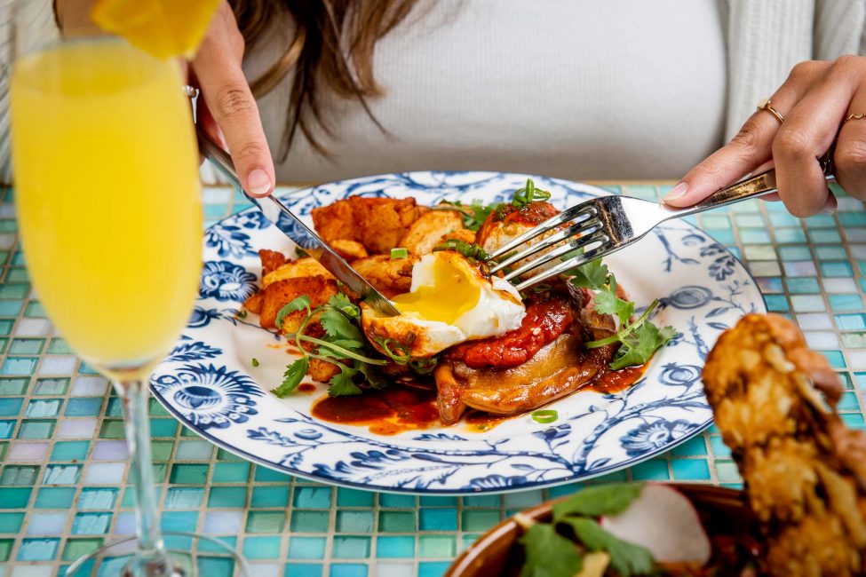 person holding fork and cutting into egg yolk in the breakfast empanada dish